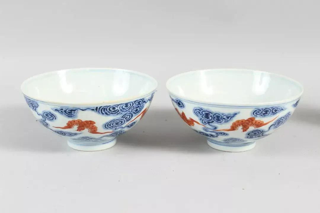 A pair of Chinese blue and white bowls decorated with iron red bats and clouds